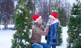 adorable niña y papá feliz con sombreros de santa al aire libre foto