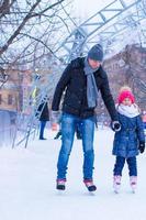 padre joven y niña adorable en la pista de patinaje al aire libre foto