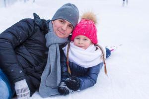 padre joven y niña adorable en la pista de patinaje al aire libre foto