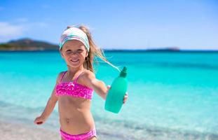 Little adorable girl in swimsuit with suntan lotion bottle photo