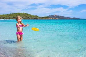 Little girl playing frisbee during tropical vacation in the sea photo