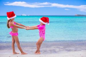 Little cute girls in Santa hats during summer vacation photo