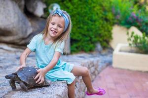 Little adorble happy girl with small turtle outdoors photo
