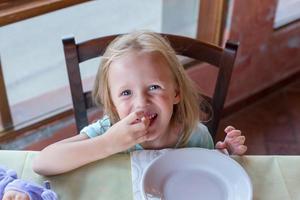 Adorable little girl having breakfast at restaurant photo