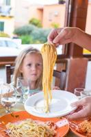 Adorable little girl having breakfast at restaurant photo