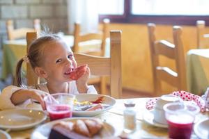 adorable niña desayunando en el restaurante foto