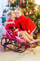 niñas vestidas como santa cerca del árbol de navidad foto