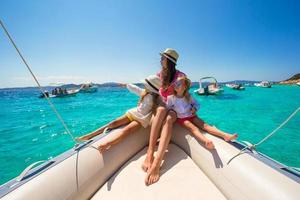 Young mother with her adorable little girls resting on a big boat photo