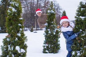 Happy father and kid in Santa hats with christmas tree outdoor photo