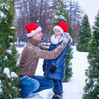 Happy family in Santa hats with christmas tree outdoor photo