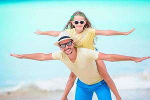 Little girl and happy dad having fun during beach vacation photo