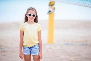 Little adorable girl playing beach volleyball. Sporty family enjoy beach game outdoors photo