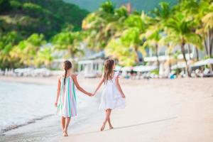 Adorable little girls walking on the beach photo