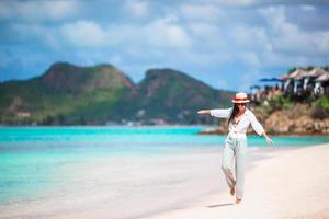 Young beautiful woman on tropical seashore. Happy girl relaxing at white sand tropical beach photo