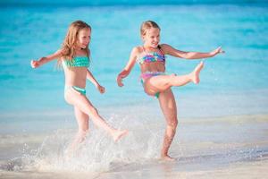 Little happy kids have a lot of fun at tropical beach playing together at shallow water. photo