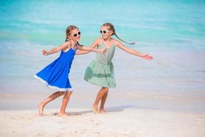 Adorable little girls have a lot of fun on the beach. Two beautiful kids are happpy photo