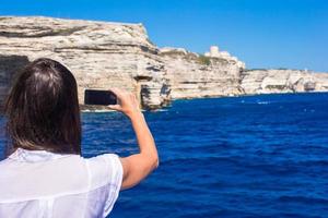 Girl taking pictures on a phone in Bonifacio, Corsica, France photo