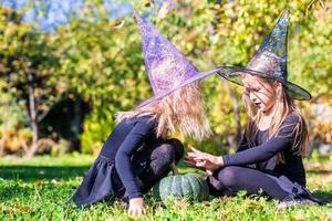 Adorable little girls in witch costume casting a spell on Halloween photo