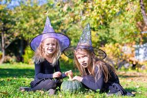 Adorable little girls in witch costume casting a spell on Halloween photo