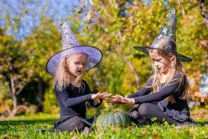 Little cute girls casting a spell on Halloween in witch costume photo