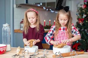 Little happy girls baking gingerbread cookies for Christmas at home kitchen photo