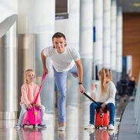 Adorable little girls with father in airport have fun waiting for boarding photo