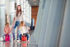 Happy family with two kids with boarding pass and luggage at airport waiting the flight photo