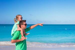 Happy father and adorable little girl outdoors during beach vacation photo