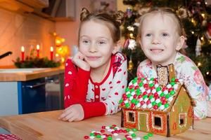 niñas felices decorando la casa de pan de jengibre para navidad foto