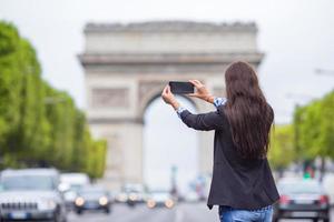 mujer joven tomando una foto con su teléfono en los campos elíseos en parís