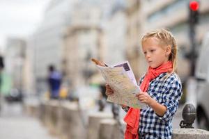 Adorable little girl with map of european city outdoors photo