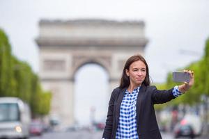 mujer joven tomando selfie con su teléfono en los campos elíseos en parís foto