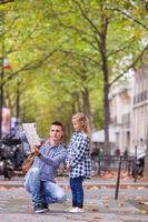 Adorable little girl and father with map of european city outdoors photo