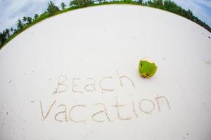 concepto de vacaciones de verano. la palabra vacaciones en la playa escrita en la arena foto