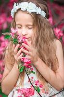 Adorable little girl enjoying smell in a flowering spring garden photo