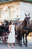 chica turista disfrutando de un paseo por viena y mirando los hermosos caballos en el carruaje foto