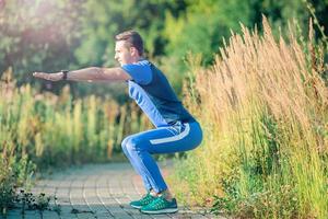 Sportive young man doing sport exercises outdoors in the park photo