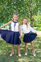 Two cute smilling little girls posing in front of their school. photo