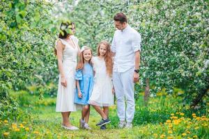 adorable familia en el floreciente jardín de cerezos en un hermoso día de primavera foto