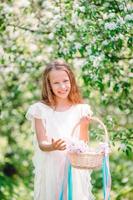 Adorable little girl in blooming apple garden on beautiful spring day photo