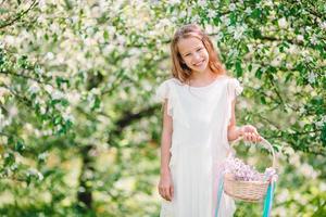 Adorable little girl in blooming apple garden on beautiful spring day photo