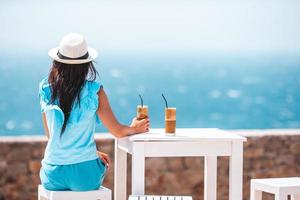 Young woman drinking cold coffee enjoying sea view photo