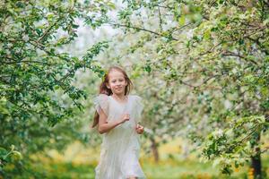 adorable niñita en un floreciente jardín de manzanas en un hermoso día de primavera foto