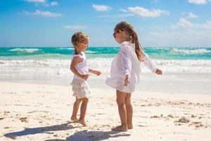 Two little sisters in white clothes have fun at tropical Mexico beach photo