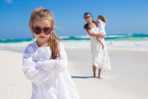 Portrait of cute girl and her mother with little sister in the background at tropical beach photo