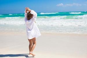 Adorable little girl dancing on an exotic white beach at sunny day photo