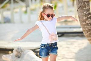 Adorable happy smiling little girl on beach vacation walks squaring arm photo