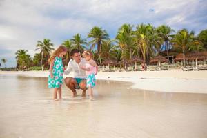 Father and his adorable little daughters playing on the beach photo