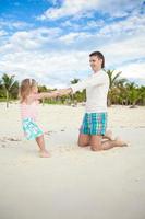 Little cute girl and her young father having fun at white beach photo