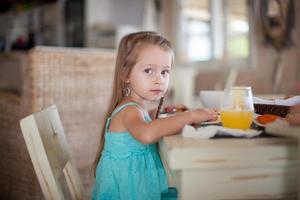 Adorable little girl having breakfast at resort restaurant photo